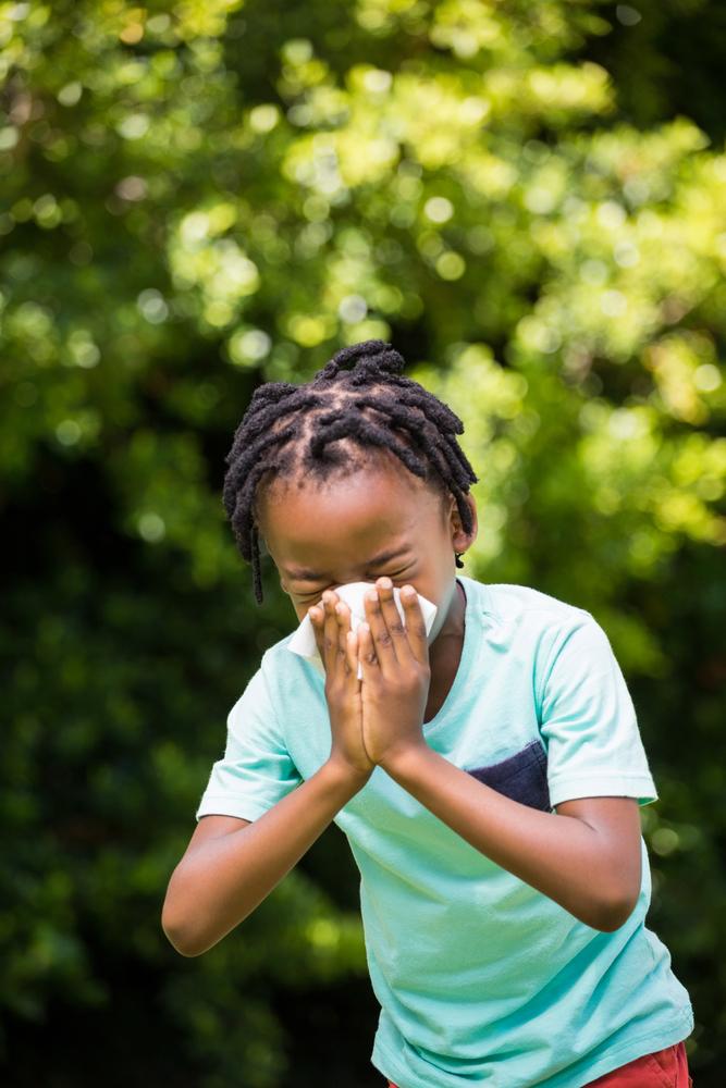A child outdoors and sneezing