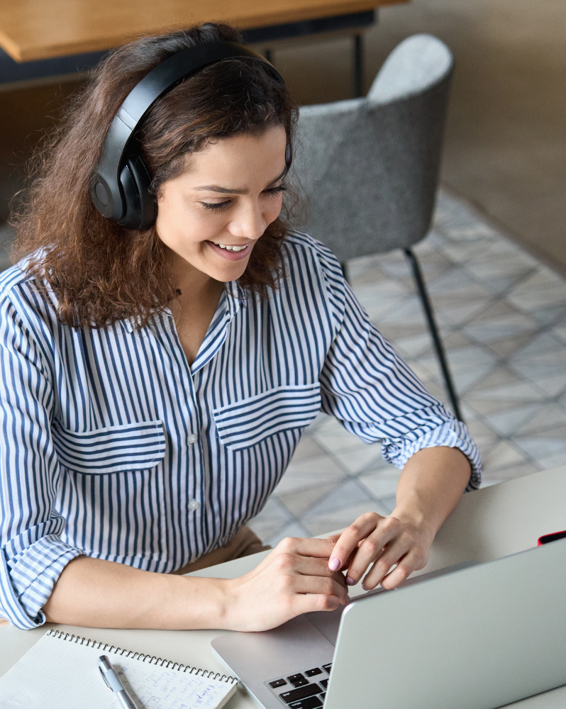 Woman wearing headphones, watching webinar on laptop