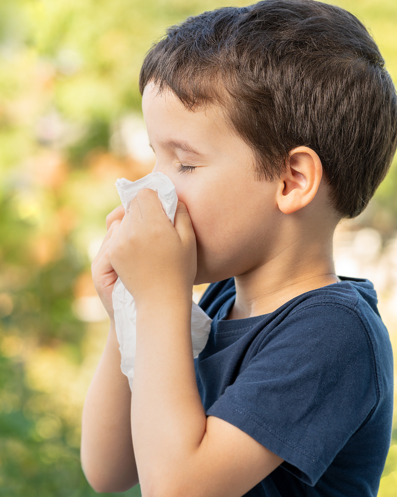 child holding a tissue after sneezing